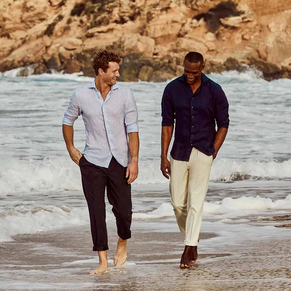 Twee mannen in linnen overhemden lopen langs de zee